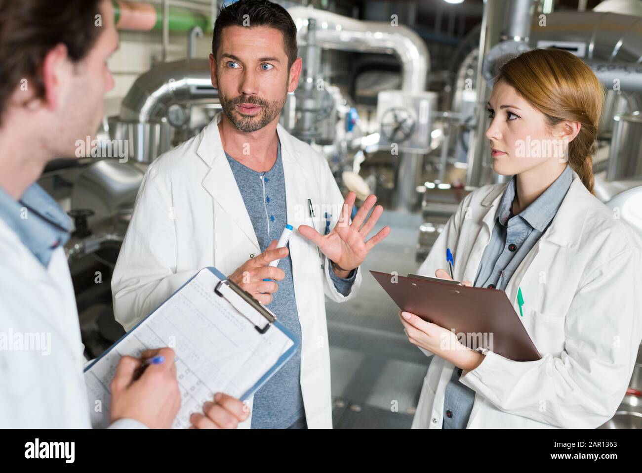 three technicians in discussion holding clipboards Stock Photo