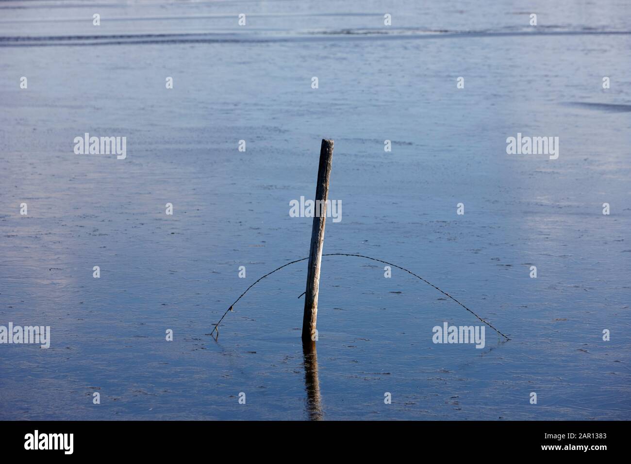 broken wire fence submerged in flooded farmland Stock Photo