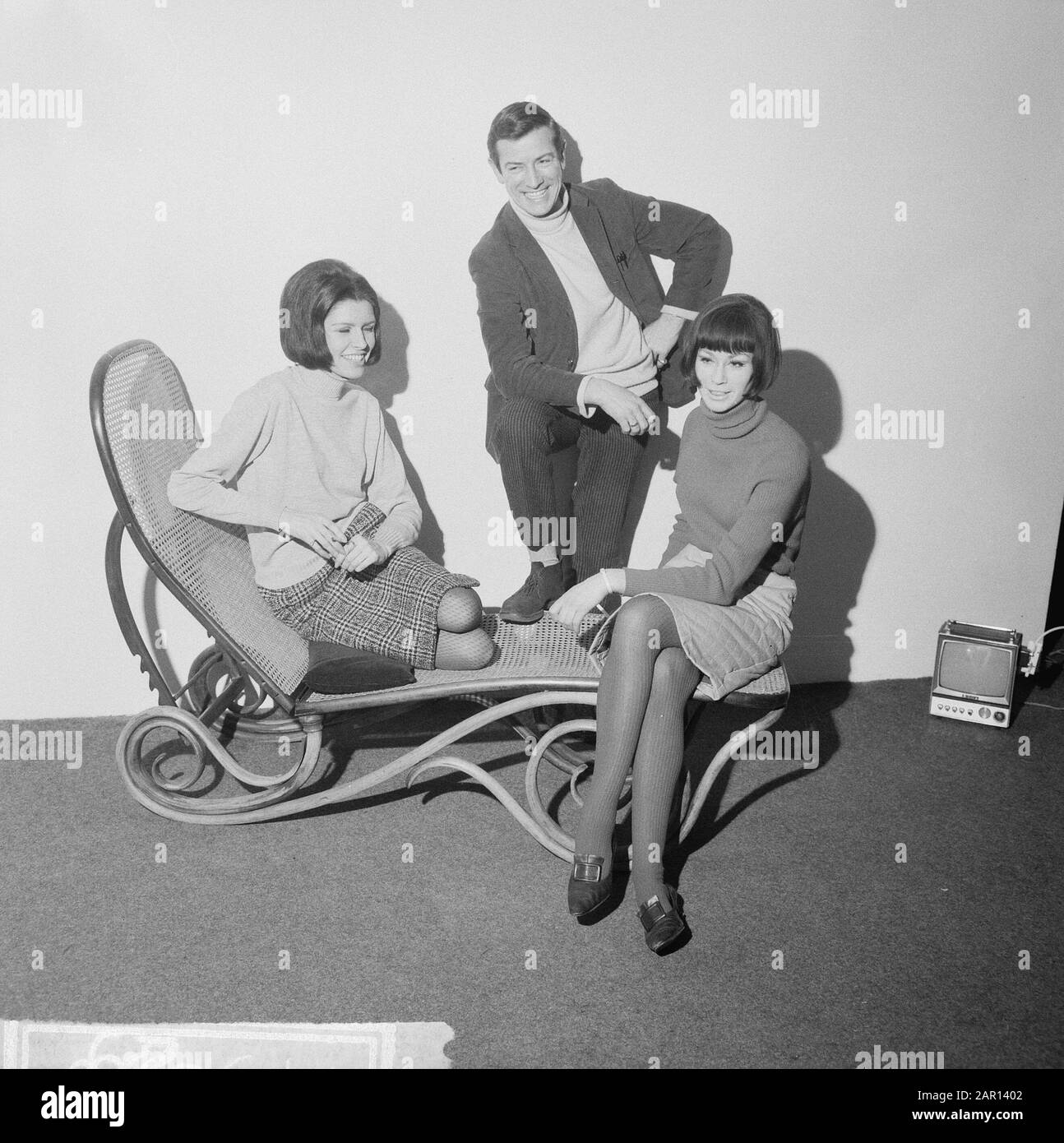 Task Telegraph Annotation: Two young women on a wicker resting chair with a man in the middle. On the right you can see a mini television Date: 28 January 1965 Institution name: Telegraph Stock Photo