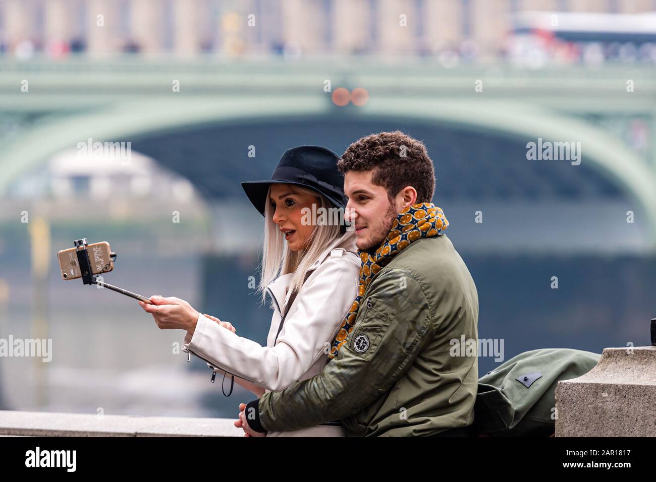 London, UK - January 1, 2020: A couple of young people take selfies with a London skyline in the background Stock Photo