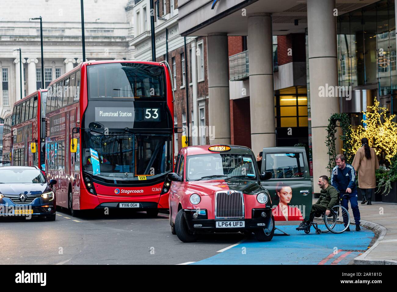 London, UK - January 1, 2020: A taxi driver helps a person with a wheelchair get in a taxi Stock Photo