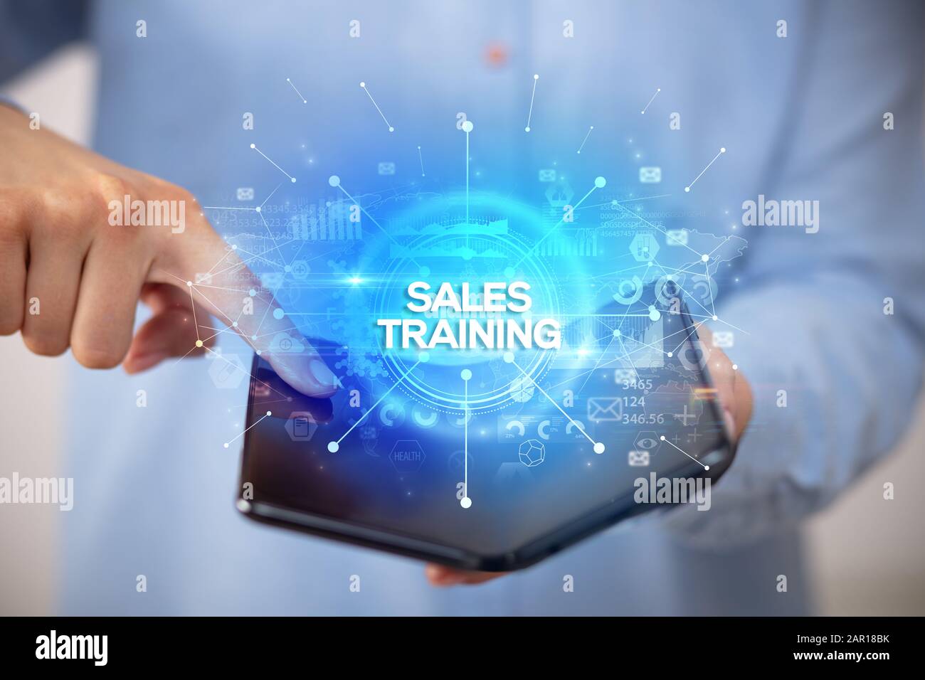 Businessman holding a foldable smartphone with SALES TRAINING inscription, new business concept Stock Photo