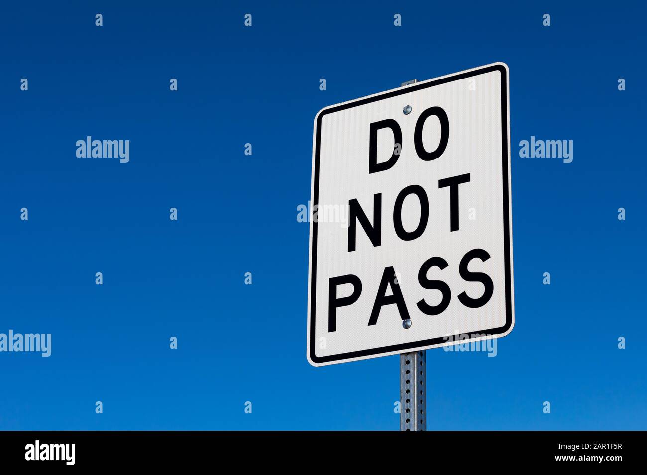 Closeup angled view of do not pass reflective street sign. Isolated on deep blue sky background Stock Photo