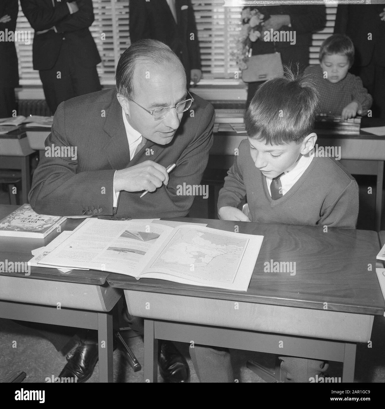Minister-President Cals during the opening of the Mr. Calsschool in Rotterdam  Minister- President Cals sitting behind a desk, next to a student Date: 27 October 1965 Location: Rotterdam, South Holland Keywords: pupils, ministers-presidents, openings, schools Personal name: Cals, Jo Stock Photo