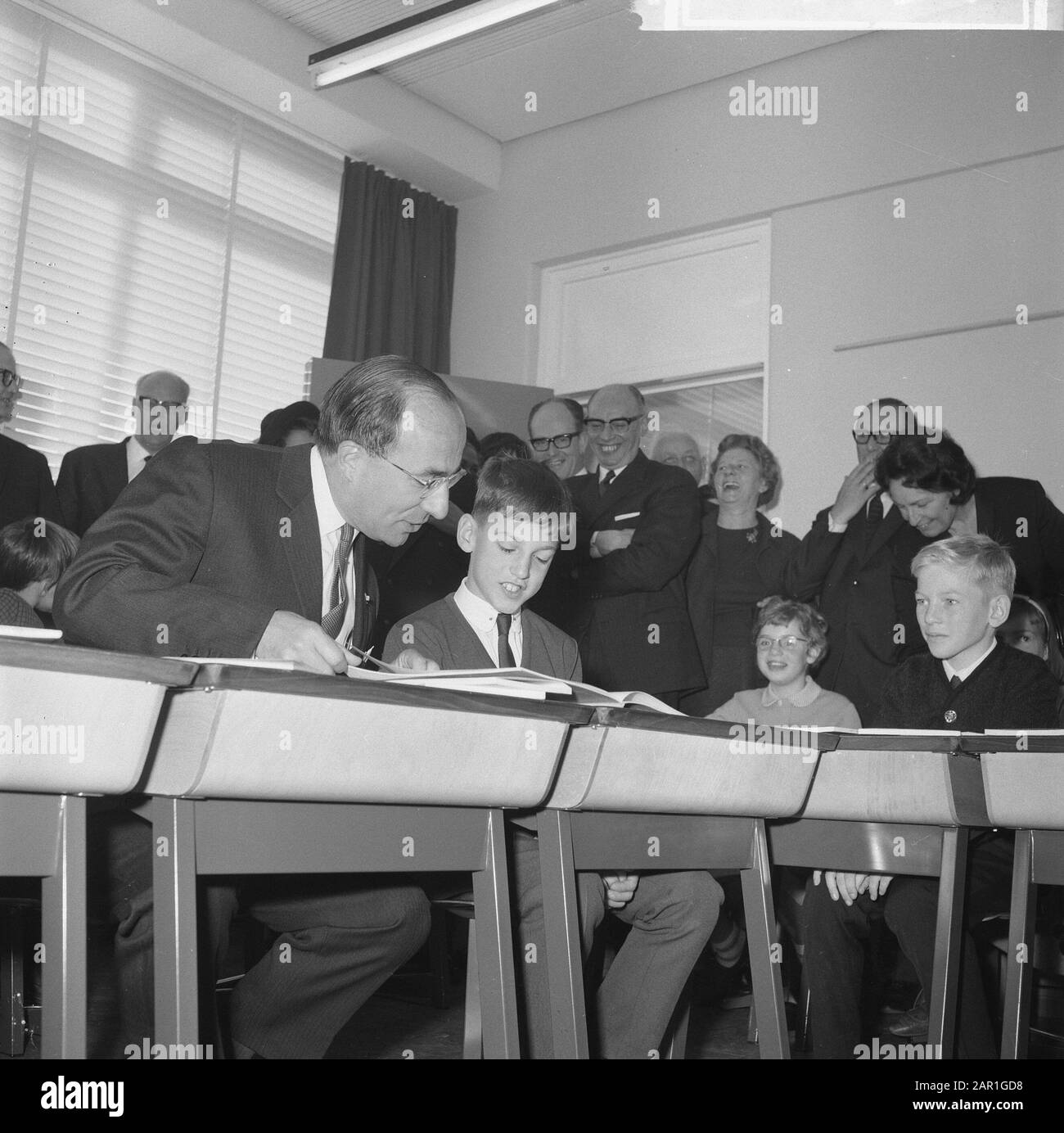 Minister-President Cals during the opening of the Mr. Calsschool in Rotterdam  Minister- President Cals sitting behind a table, next to a student Date: 27 October 1965 Location: Rotterdam, South Holland Keywords: pupils, ministers-presidents, openings, schools Personal name: Cals, Jo Stock Photo