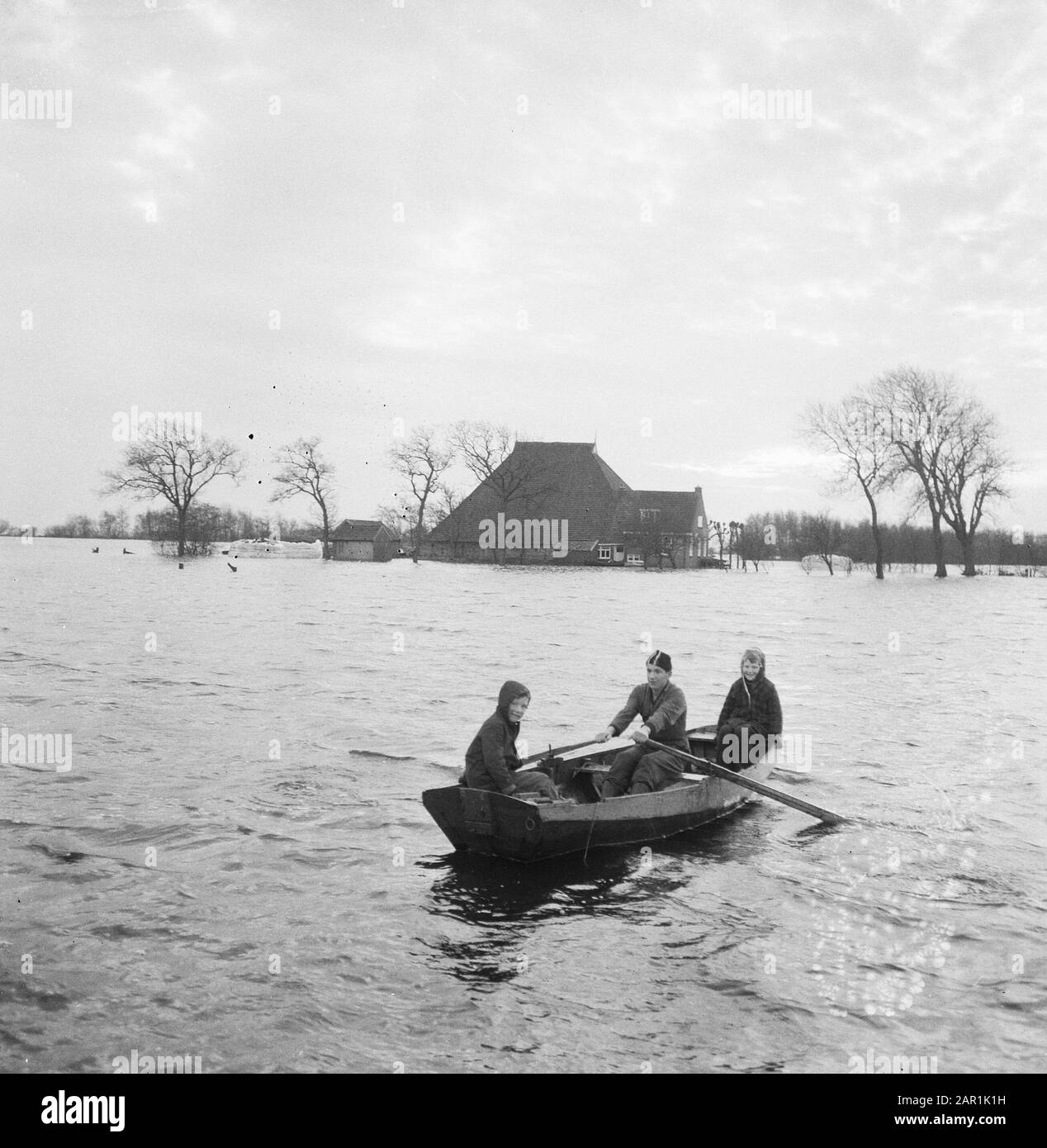 Flood in Friesland, family Oeneman in Alde Ouer near Joure must evacuate; children in a rowing boat on their way to a farm Date: 19 December 1965 Location: Friesland, Joure Keywords: farms, children, floods, rowing boats, waterlogging Stock Photo