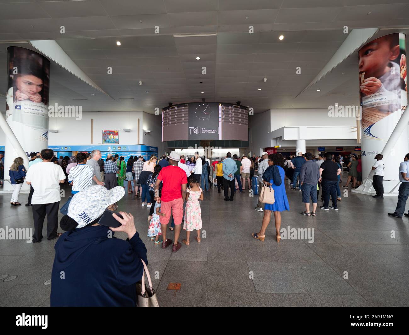 New York, USA - June 2, 2019: Passengers look at the information panel of arrivals and departures from JFK gate 4. Stock Photo