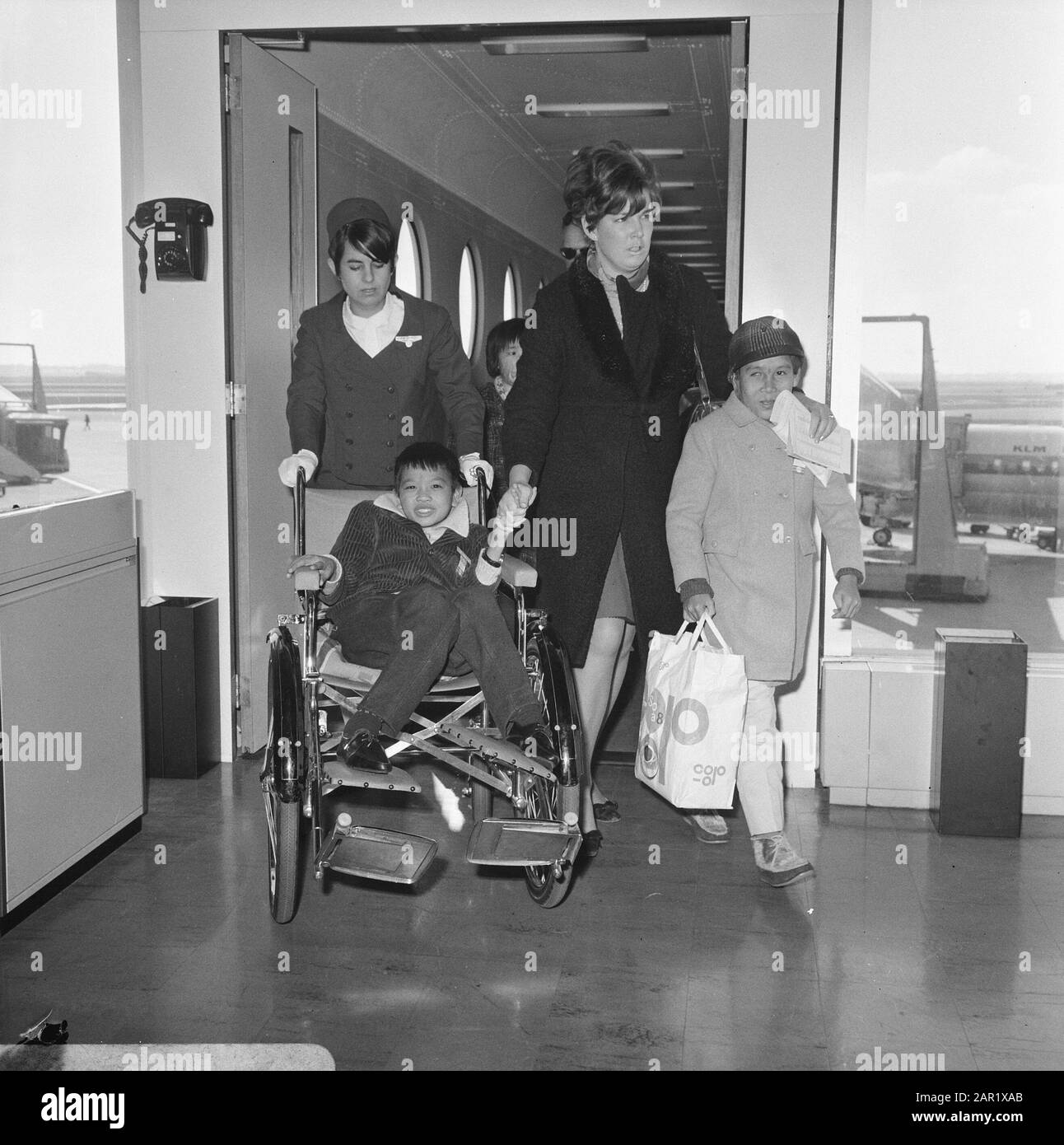 Arrival Vietnamese children at Schiphol  Three children from Vietnam arrived at Schiphol Airport who were seriously injured there by the war. The children, two girls and a boy, were brought to the Netherlands by the foundation Terre des Hommes. His are going to a clinic in Huizen (N.H.). Two of the three children on arrival at Schiphol Airport, in the chair the boy (injured by mine explosion) and on the right a girl (burns) Date: 27 February 1968 Location: Noord-Holland, Schiphol Keywords: arrivals, health care, children, patients, airports Stock Photo