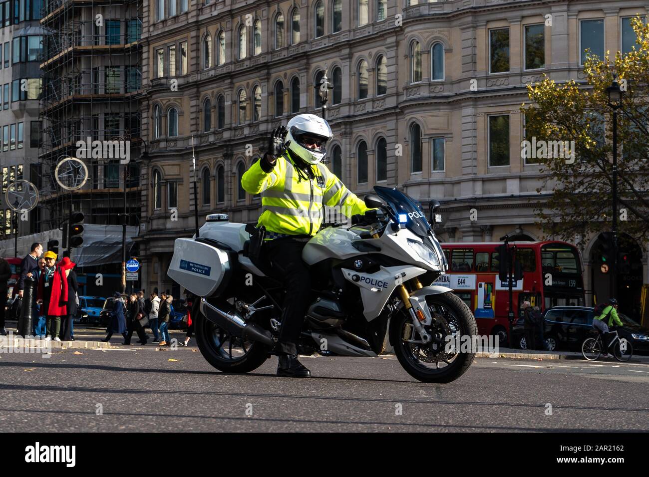 LONDON, UNITED KINGDOM - Nov 11, 2019: British police officer on motor bike stops car traffic at busy trafalgar square intersection for government esc Stock Photo