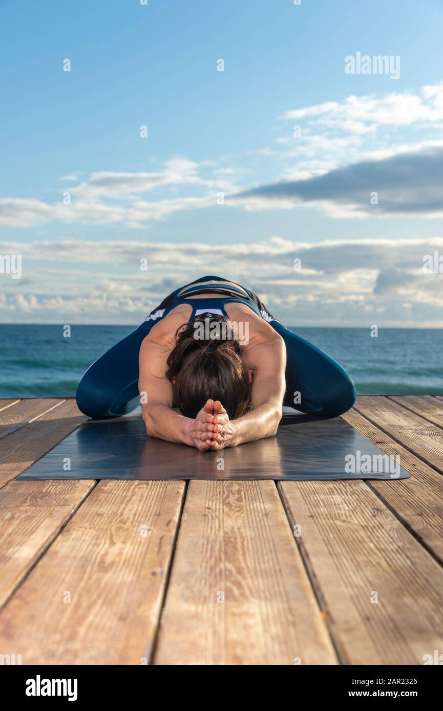 woman practicing child's asana yoga pose outside by the sea. Utthita Balasana pose Stock Photo