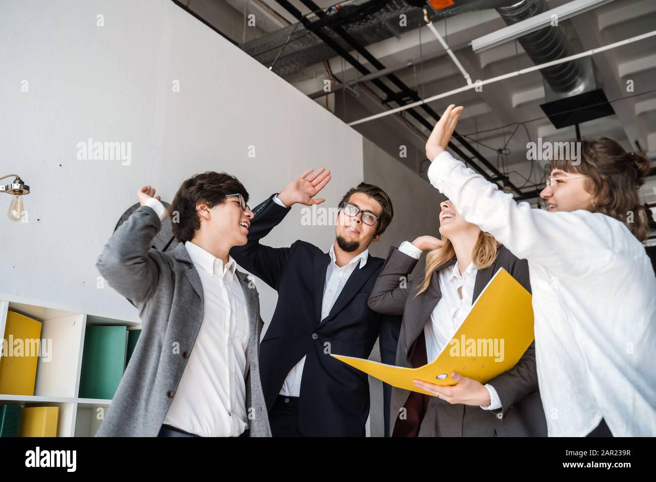 Cheerful young group of people standing in the office and giving high ...