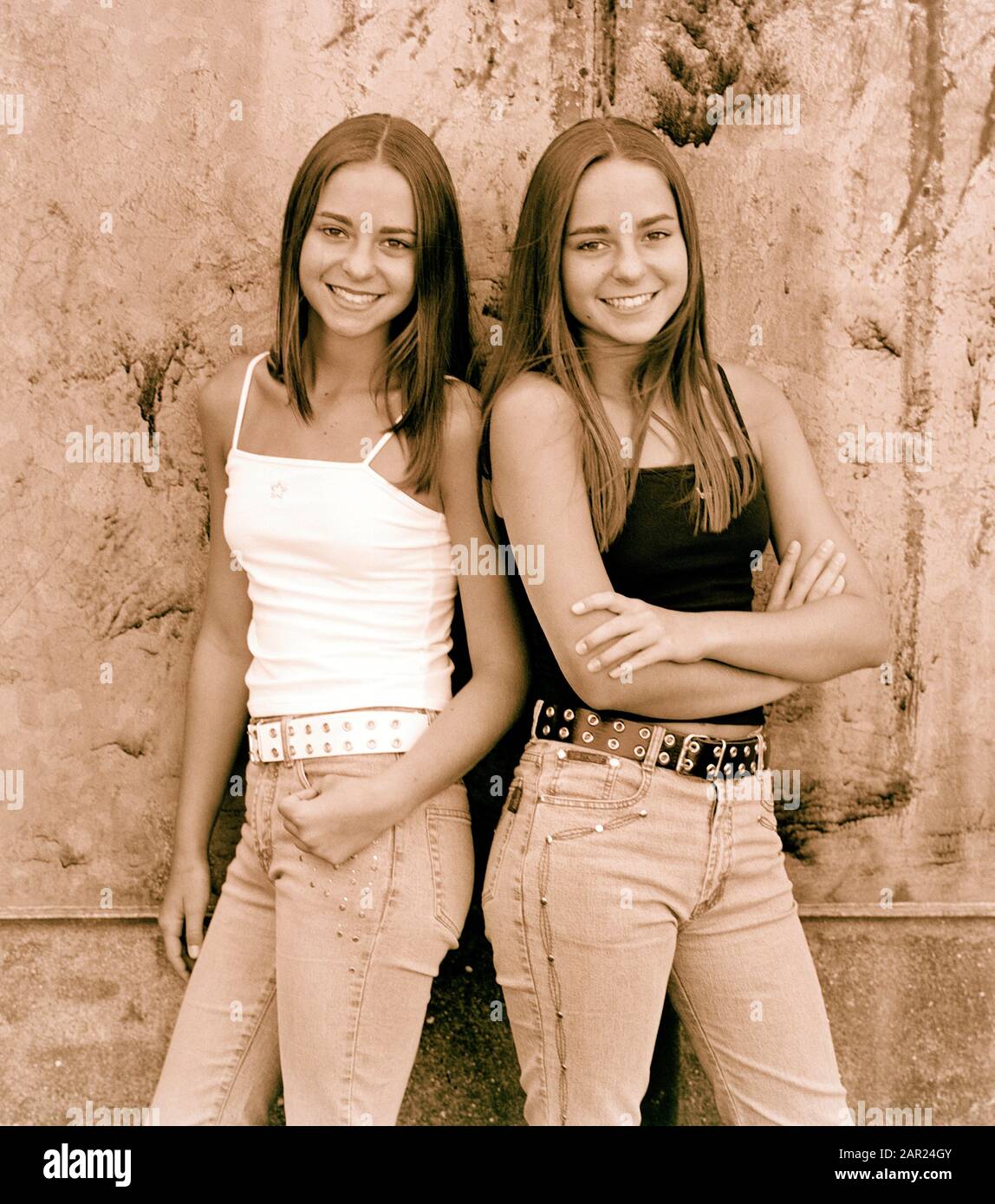 Teenage Twin Girls Standing By Wall Outdoors Stock Photo Alamy