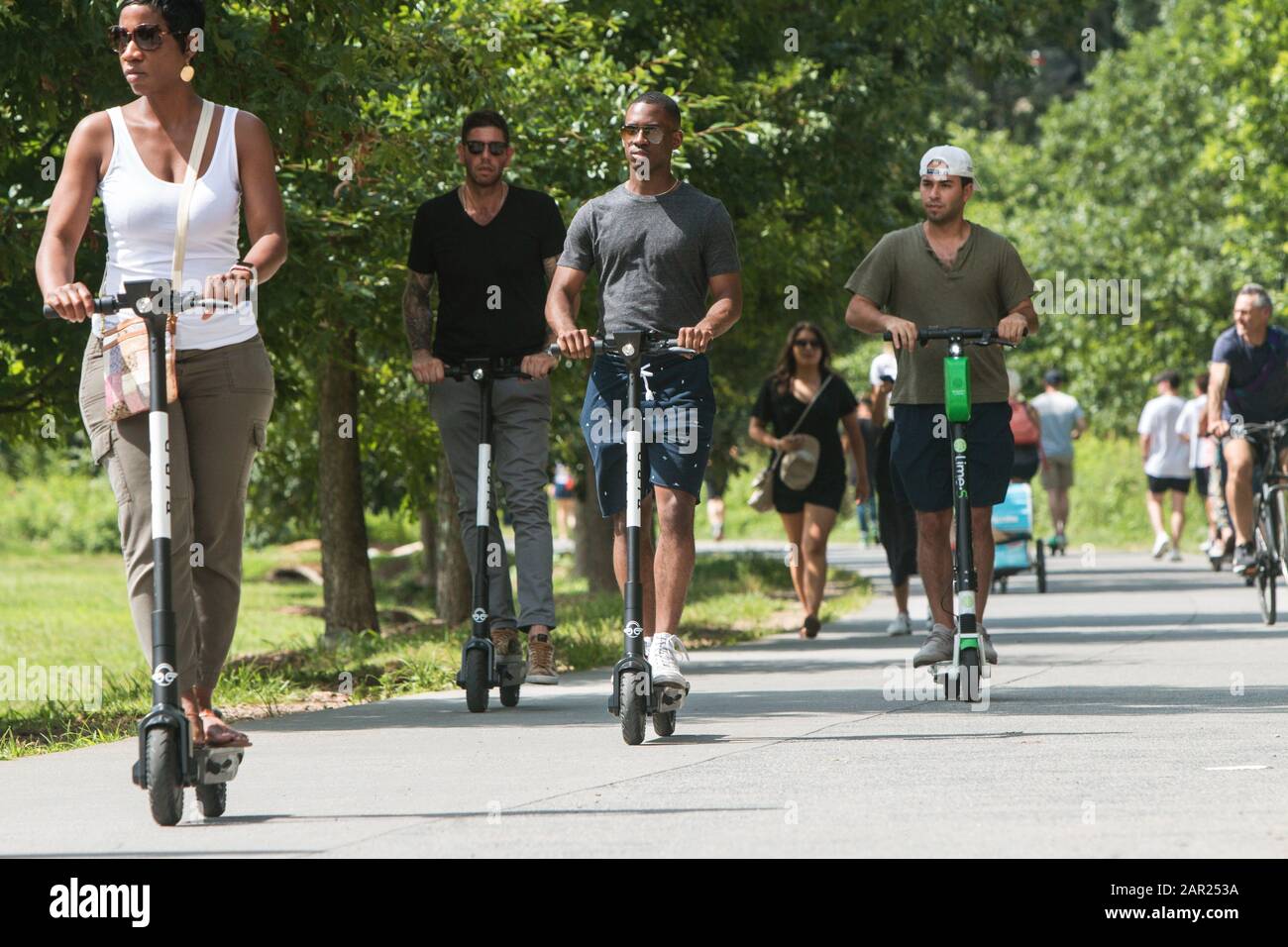 Diverse people ride motorized scooters along the Atlanta Belt Line at