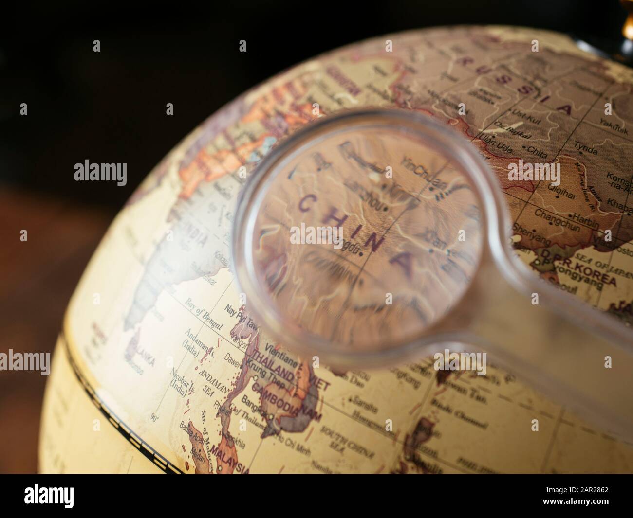Magnifying glass focusing in on China on a globe. Stock Photo