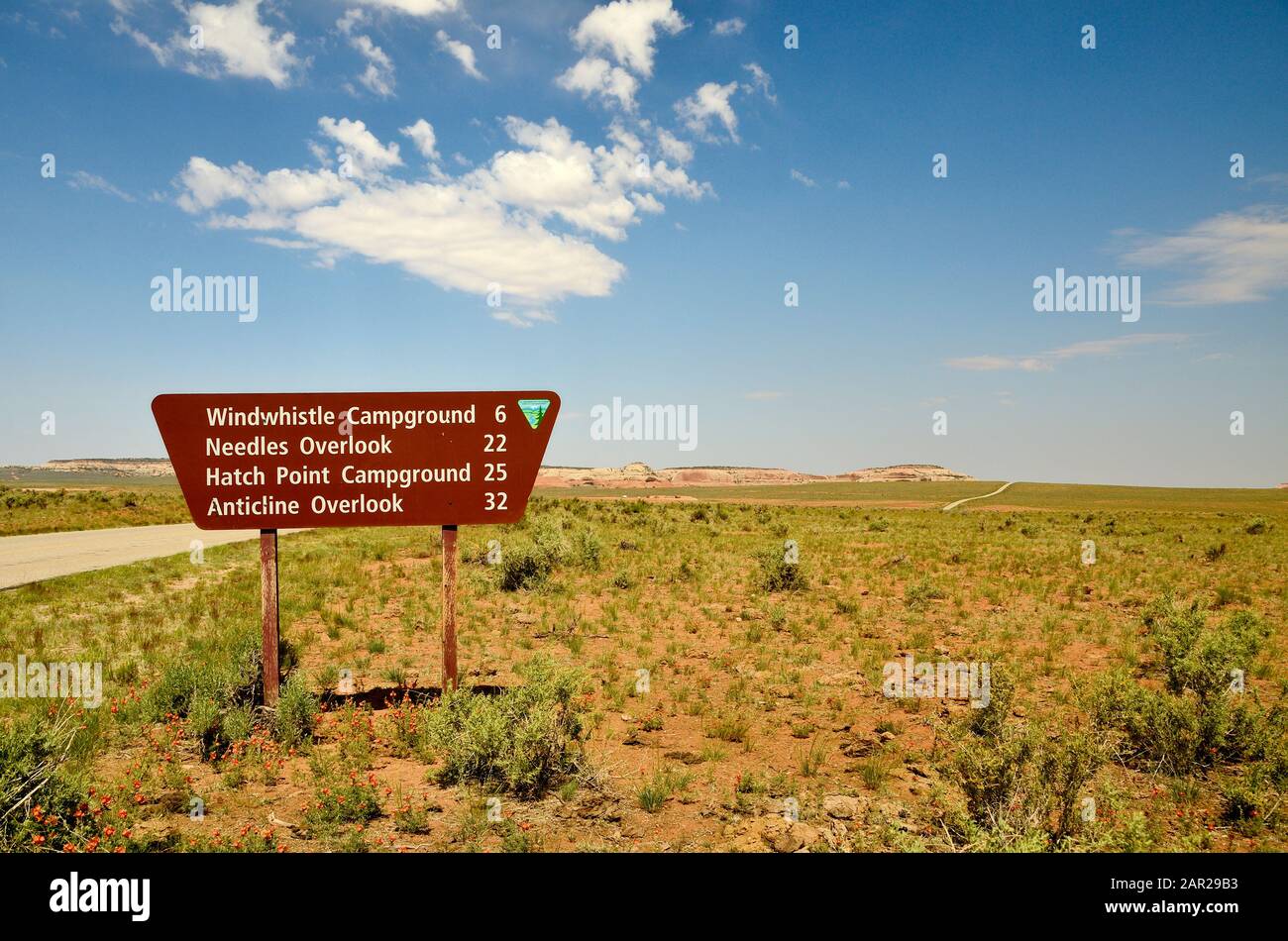brown road sign indicating the distance to different destinations, in the background blue sky with white clouds. Stock Photo