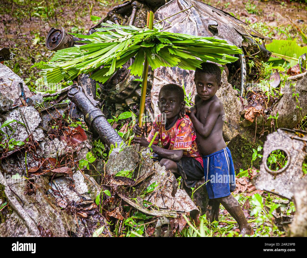 Two boys with self-made rain umbrellas in the jungle of Bougainville, Papua New Guinea Stock Photo