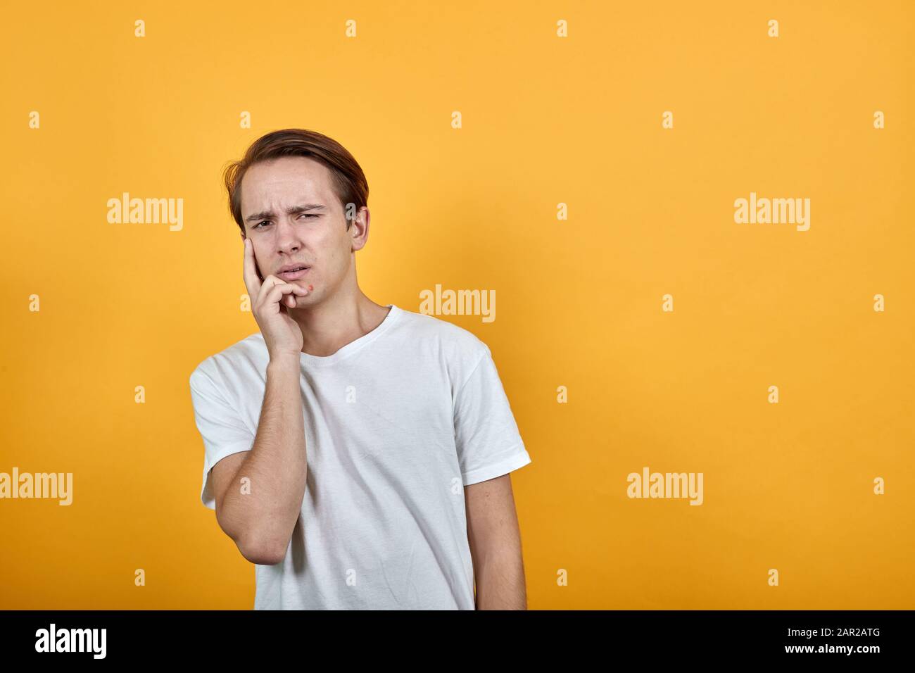 Sad man holds hand on face with acne. Stock Photo