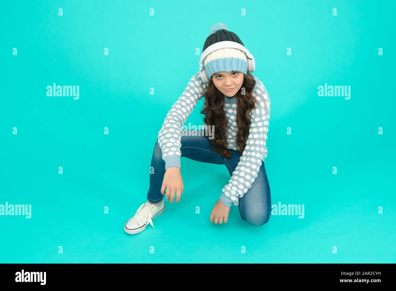 Cool Kid Turquoise Background Music For Winter Playlist Favorite Winter Song Girl Enjoy Favorite Tune Music Mood Small Child Knitted Sweater And Hat She Is Listening To Music On Headphones Stock Photo