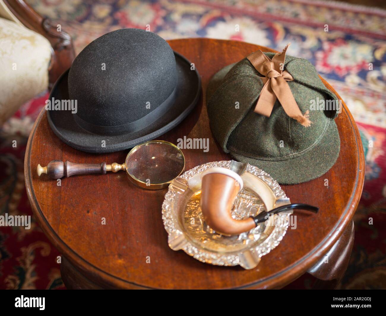 Sherlock Holmes Typical Objects on a Little Wooden Table: Deerstalker, Pipe, Magnifier. Stock Photo