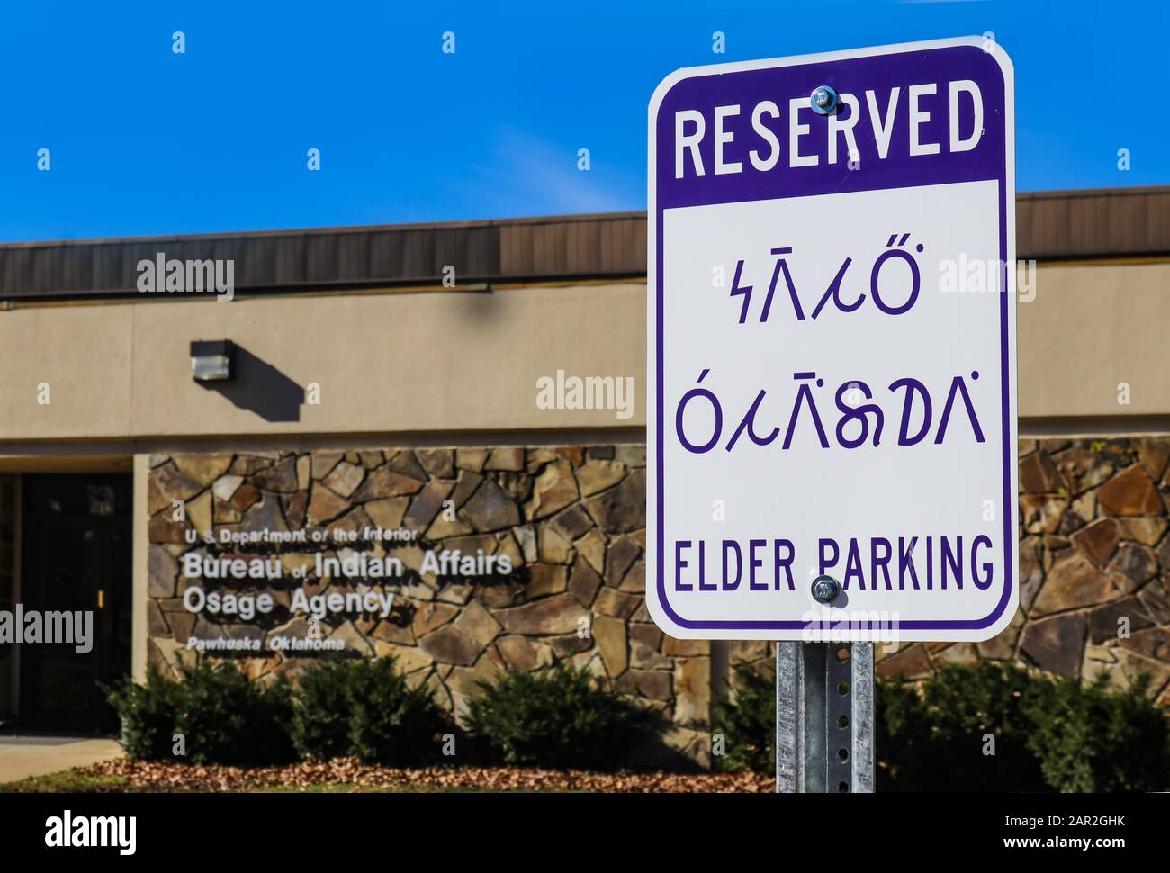 Reserved - Elder Parking sign in English and the Osage Indian Language (Wazhazhe) outside the Bureau of Indian Affairs Osage Agency in Pawhuska Ok USA Stock Photo