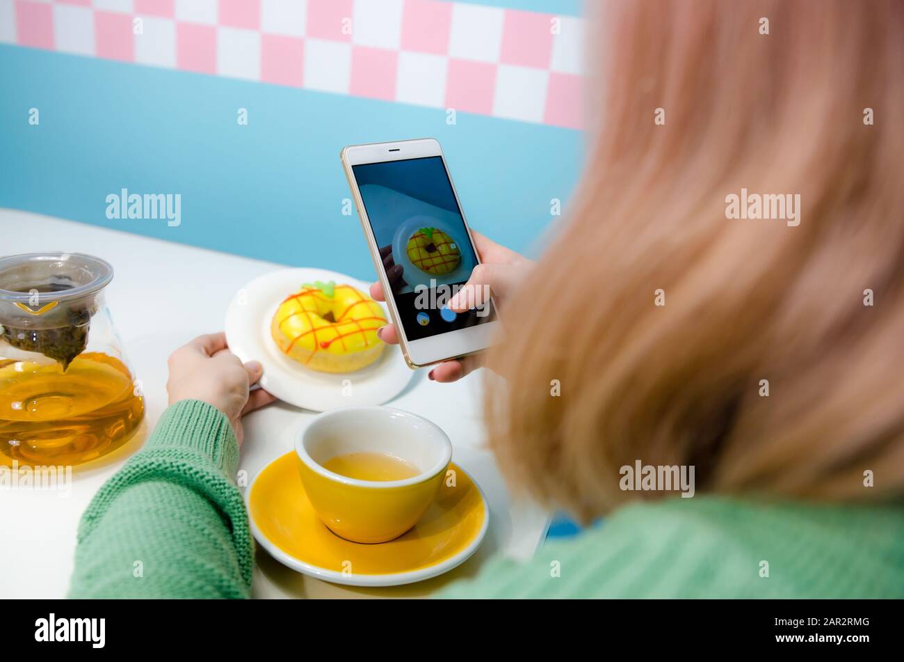 Closeup of women's hands making photo of donut with tea Stock Photo