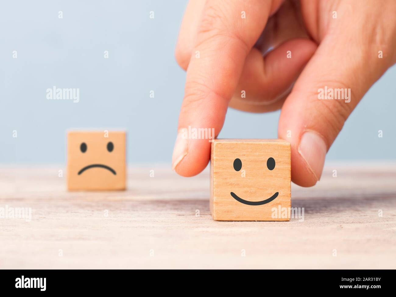 hand chose smiley face front of sad face.customer satisfaction concept Stock Photo