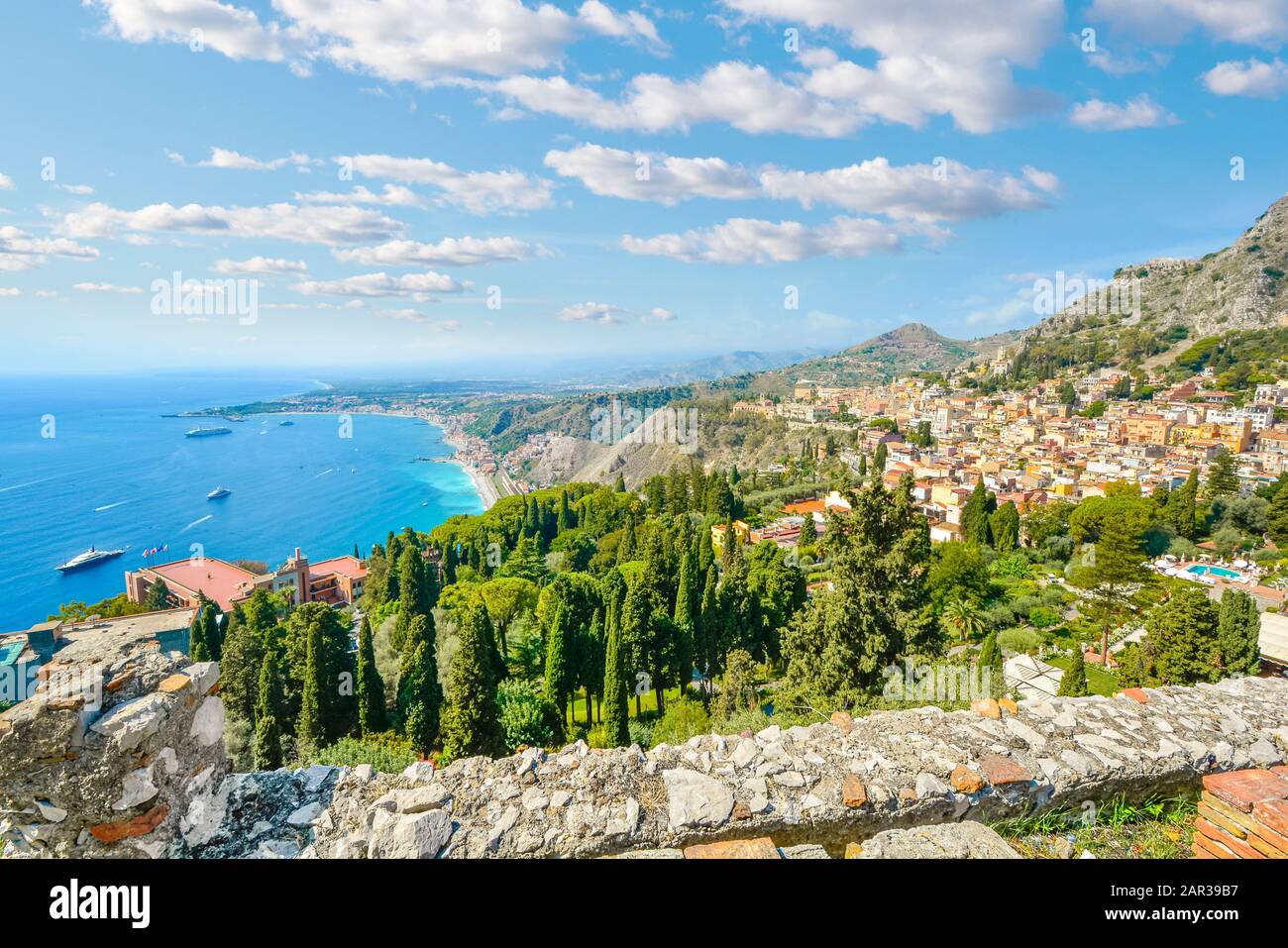 Looking down from the ancient Greek Theatre at Taormina, Italy, on the Italian island of Sicily, with boats and resorts dotting the Mediterranean sea Stock Photo
