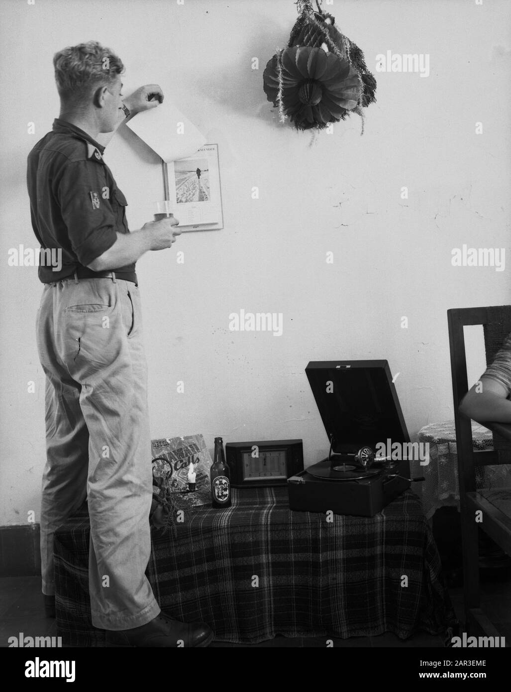 Man in uniform with sleeve emblem War Volunteer KL tears off a sheet of a calendar of the year 1947. Posted photo Date: 1947/01/01 Location: Indonesia, Dutch East Indies Stock Photo