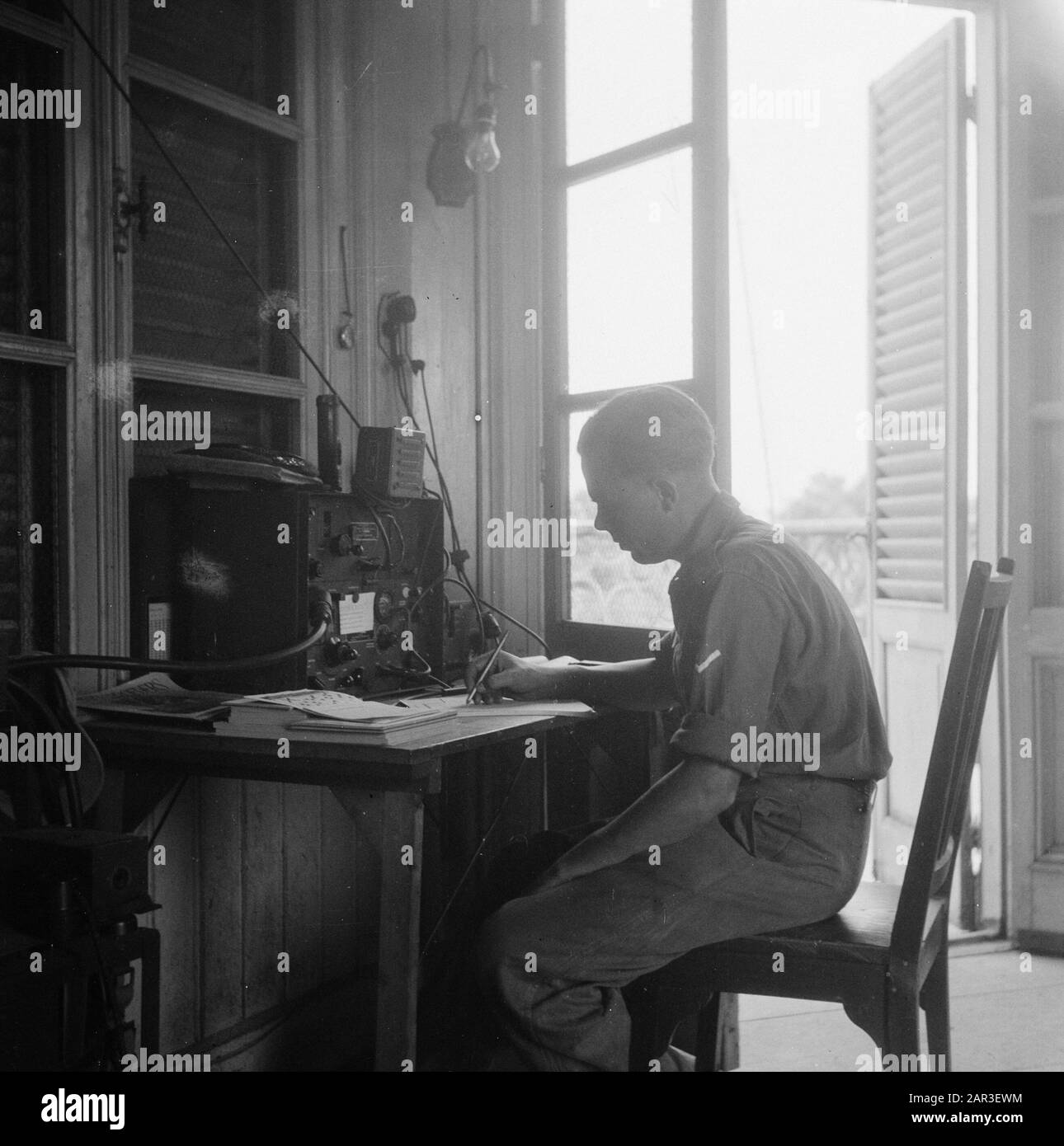 [Radio telegraphist notes something on a sheet of paper] Date: 1947/01/01 Location: Indonesia, Dutch East Indies Stock Photo