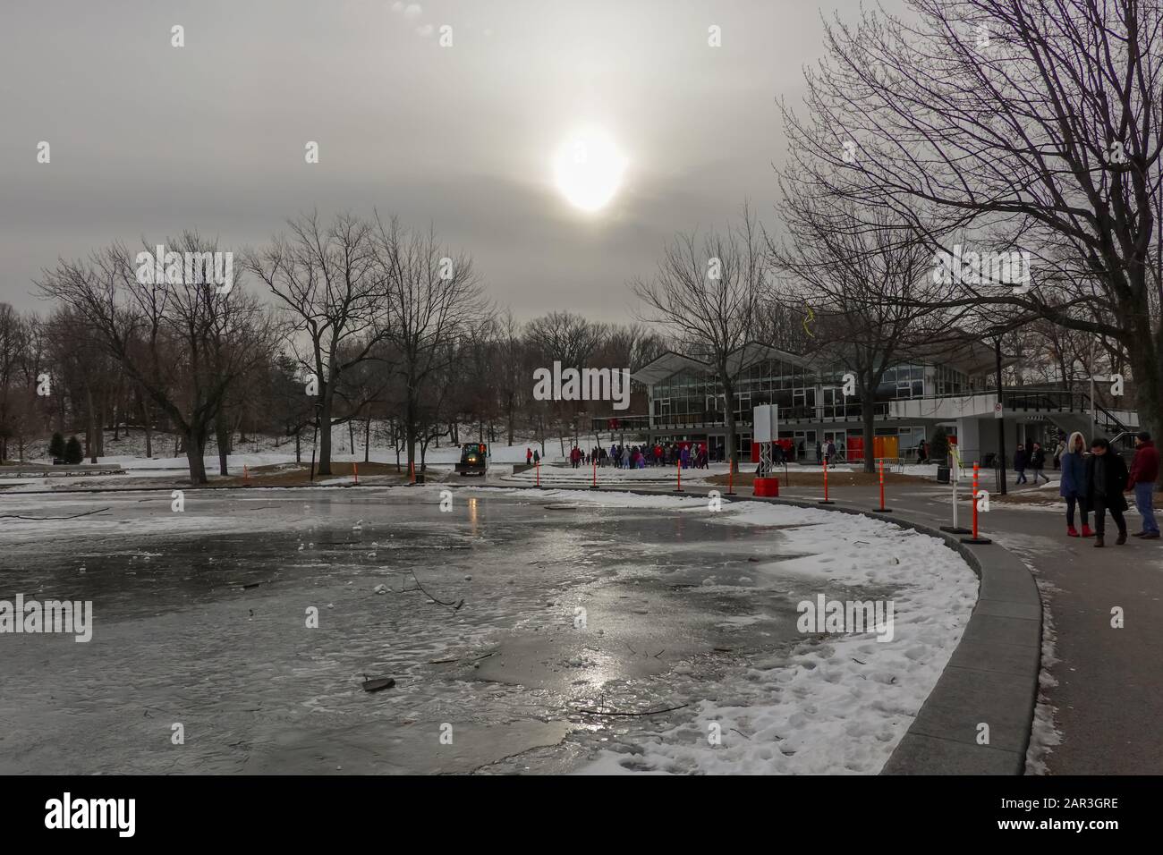sun covered by clouds sunlight reflecting to the ice sheet of a lake in mont royal park in quebec during winter in 2020 Stock Photo