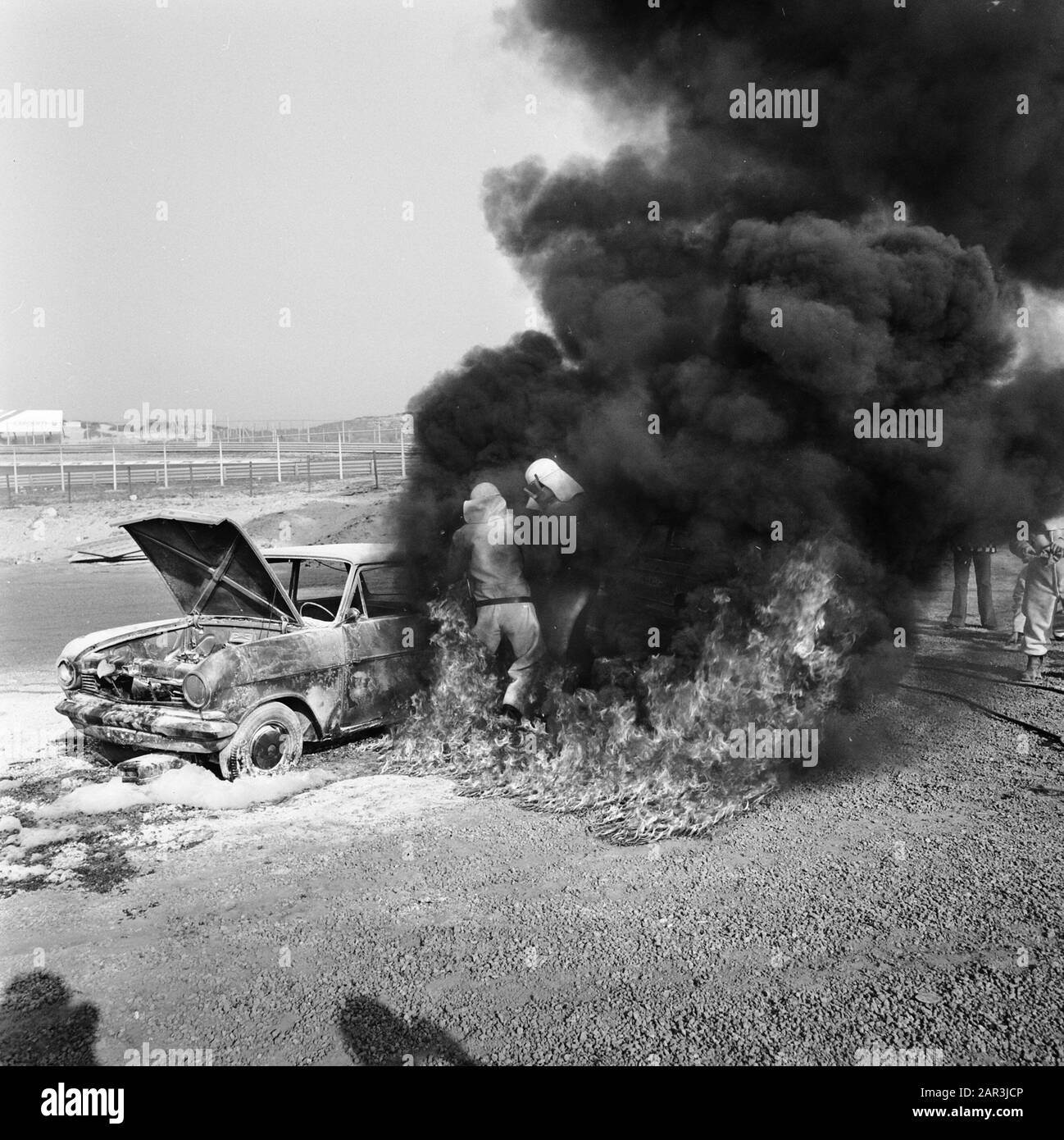 Rescue demonstration at Zandvoort circuit, volunteers with equipped BMW extinguishing burning wreck Date: 9 april 1974 Location: Noord-Holland, Zandvoort Keywords: VOLUNTERS, demonstrations Stock Photo