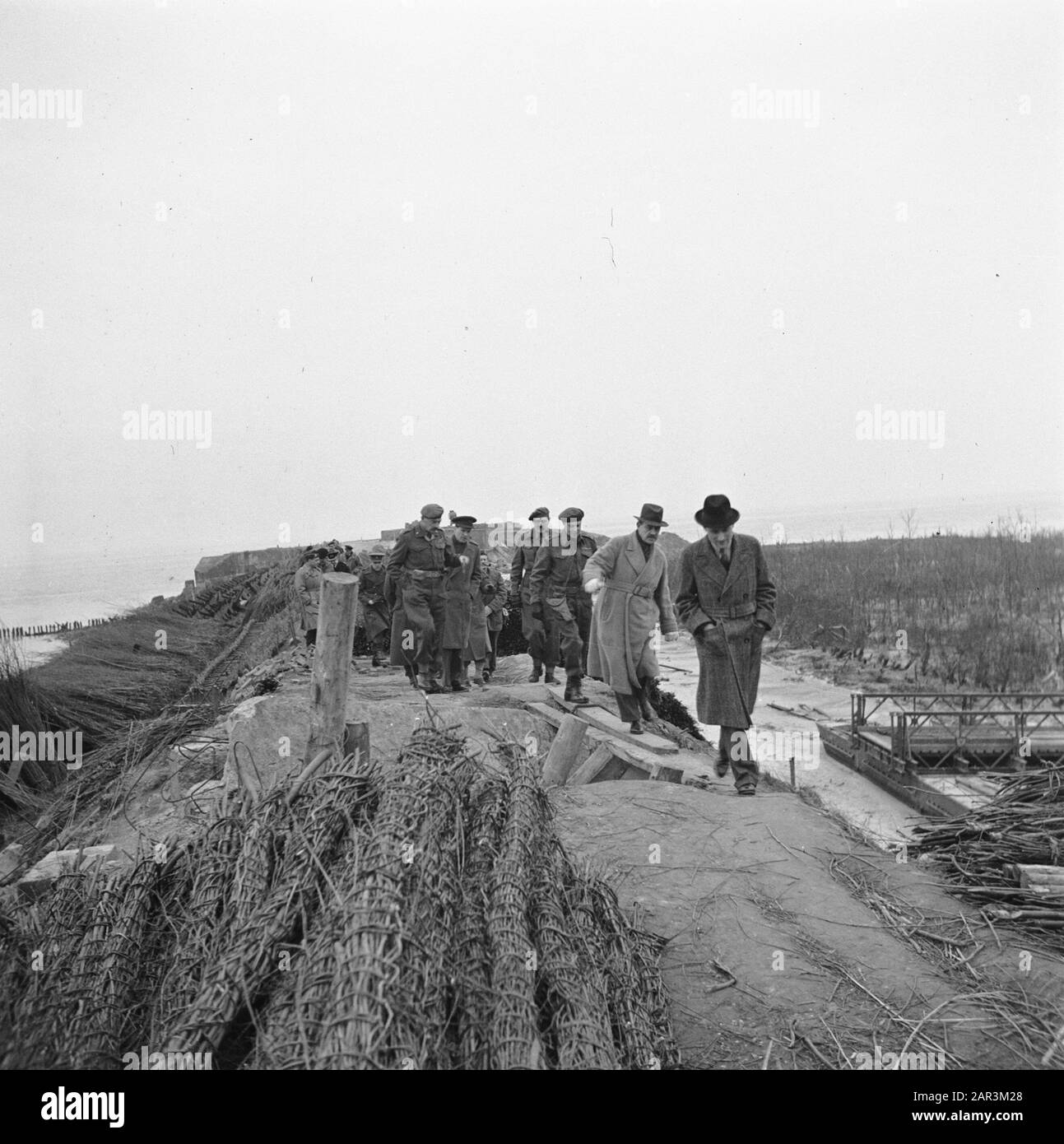 Devastations: Zeeland [Visit by British Minister Attlee to the destruction and inundations on Walcheren]  The company military and civilian authorities during a walk along the destroyed coastal defense Annotation: Lingmats for the restoration of the dikes are already ready Date: 10 March 1945 Location: Vlissingen, Walcheren, Zeeland Keywords: military, ministers Personal name: Attlee, C.R. Stock Photo