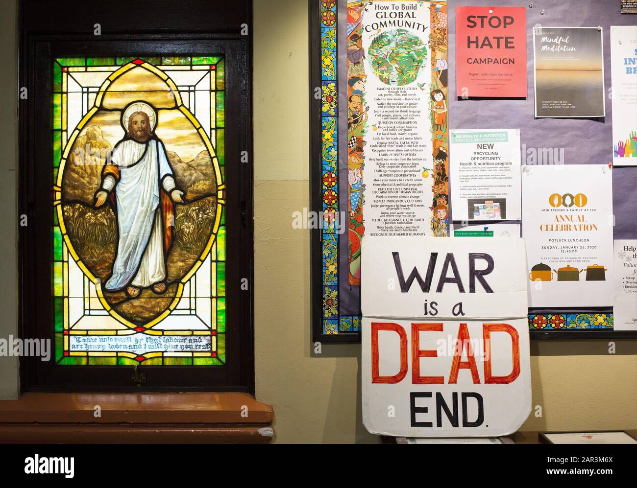 An antiwar sign next to a stained glass window of Jesus, in a church