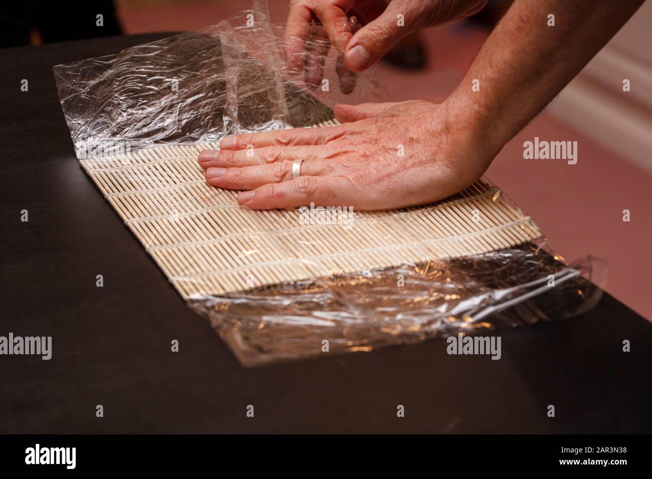 Chef Preparing Sushi Mat With Plastic Wrap To Make A Roll For A