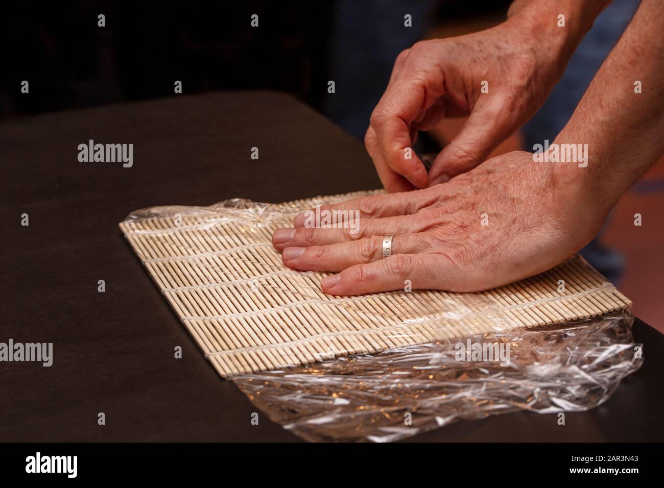 Chef Preparing Sushi Mat With Plastic Wrap To Make A Roll For A