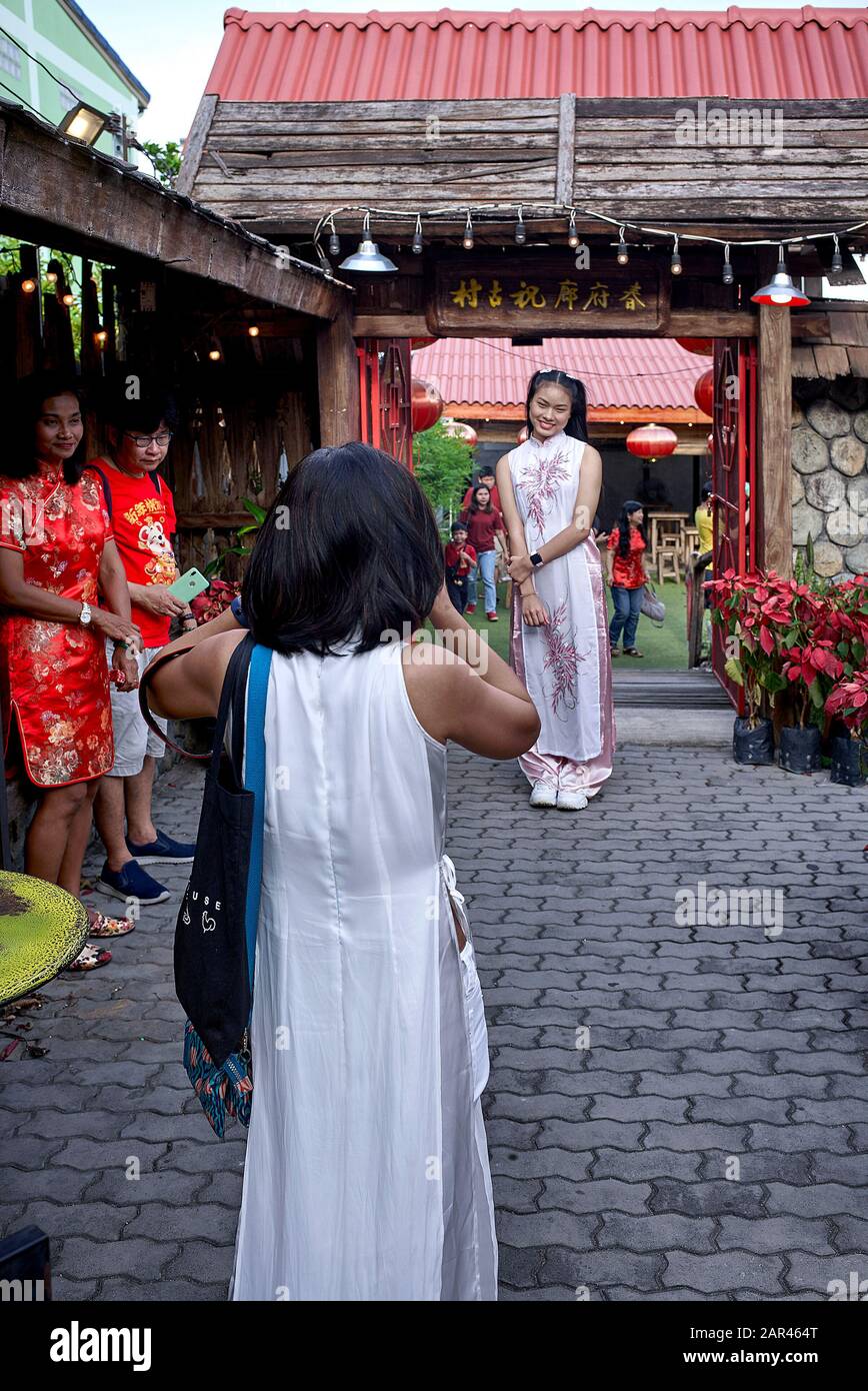 Mother taking photo of adult daughter both dressed áo dài traditional Vietnamese costume; Mother photograph daughter Stock Photo