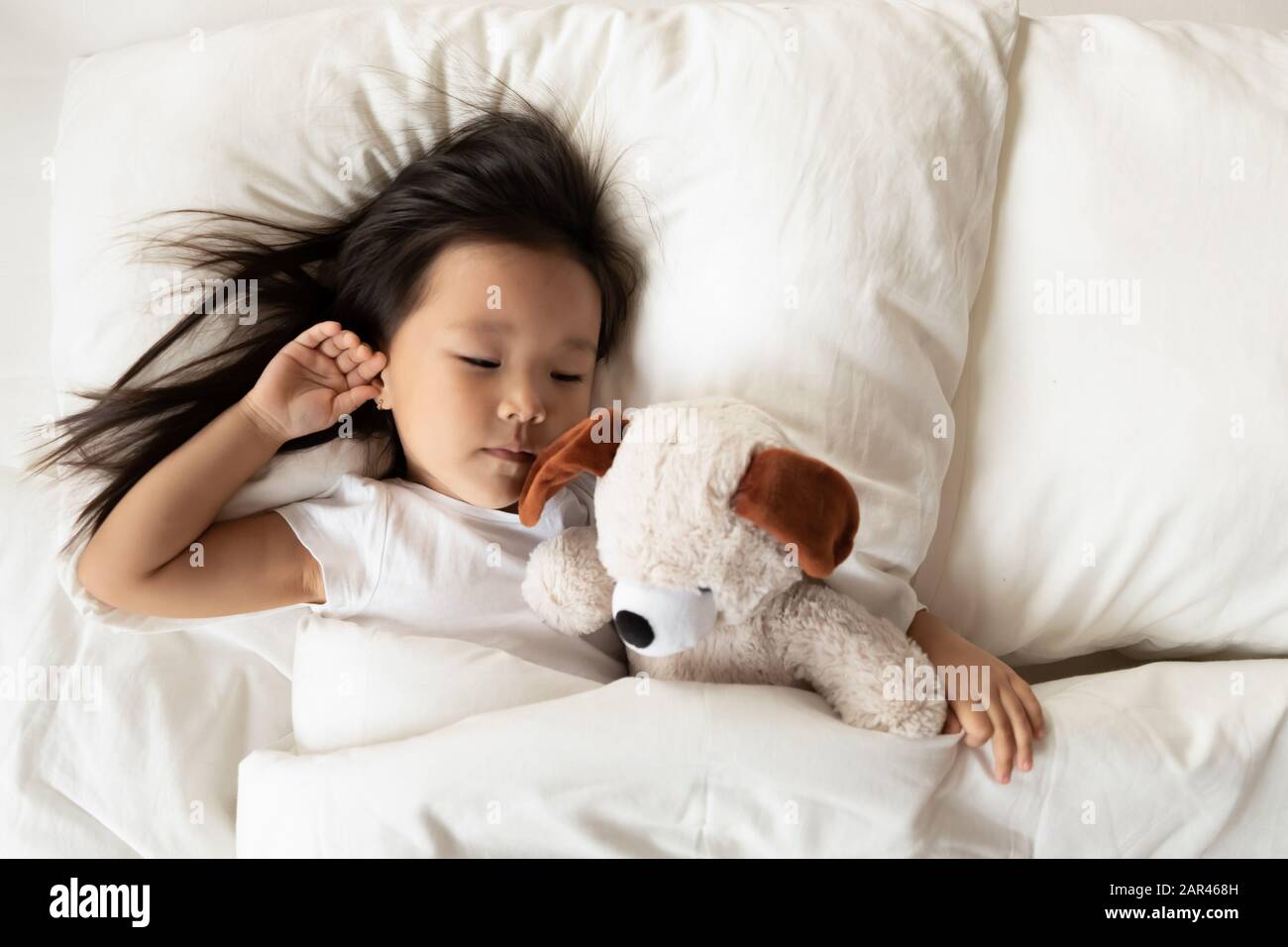 Small Asian girl sleep in bed with fluffy toy Stock Photo