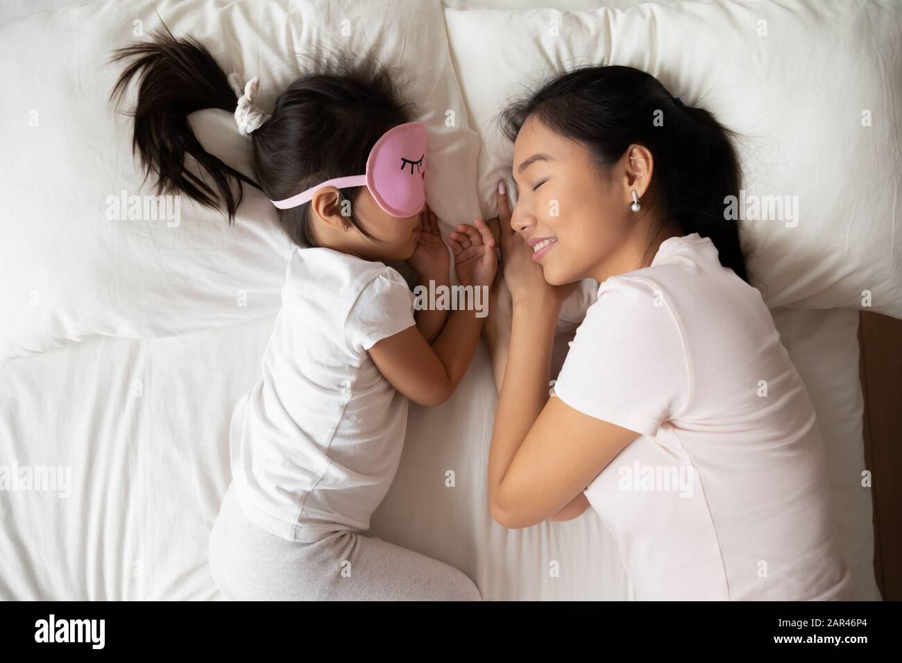 Asian young mum and little daughter sleep in cozy bed Stock Photo