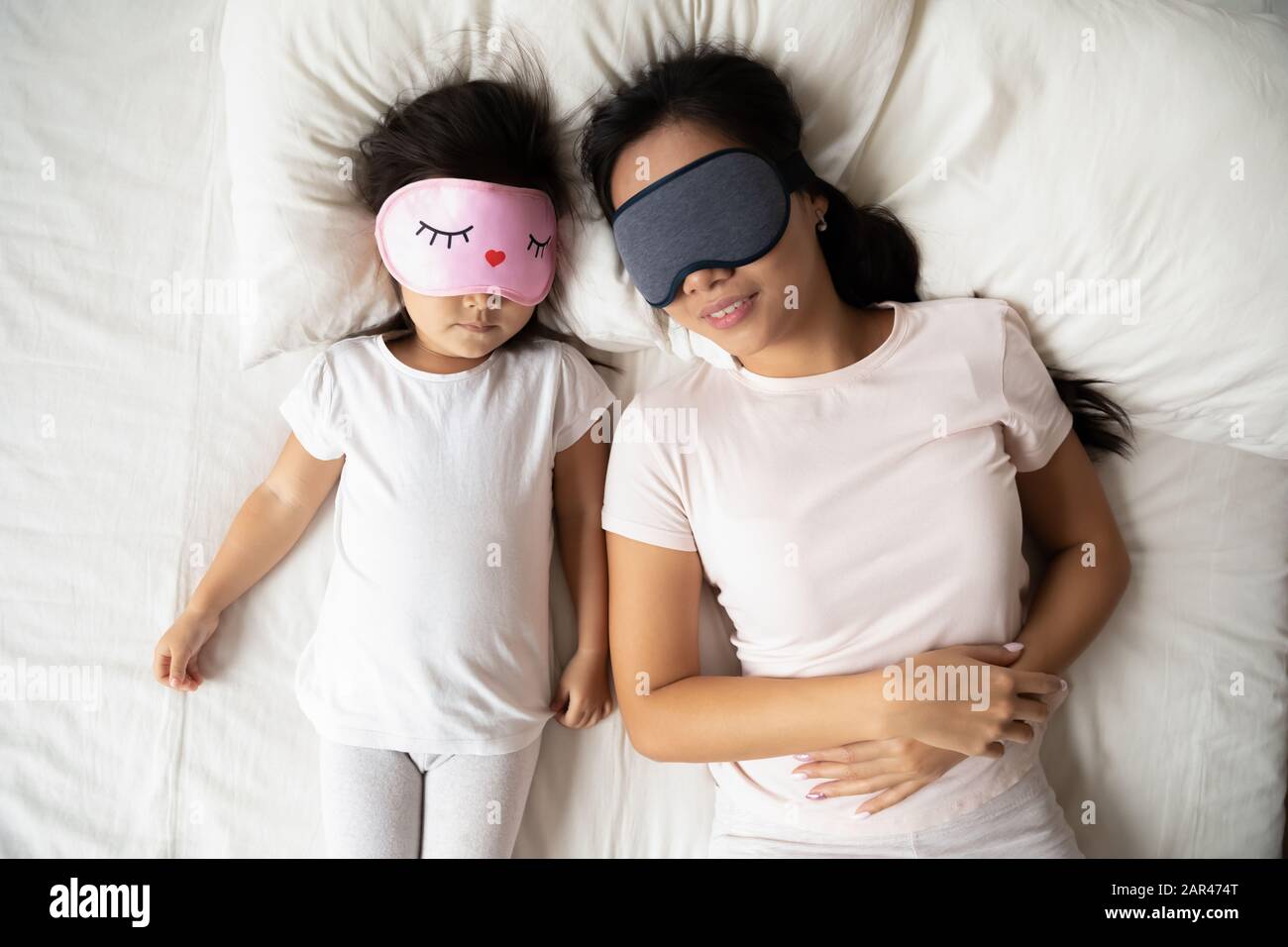 Calm Vietnamese mother and small daughter daydream in bed Stock Photo
