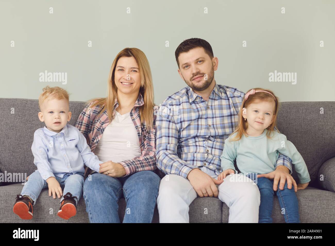 Happy funny family with children smiling sitting on a sofa Stock Photo