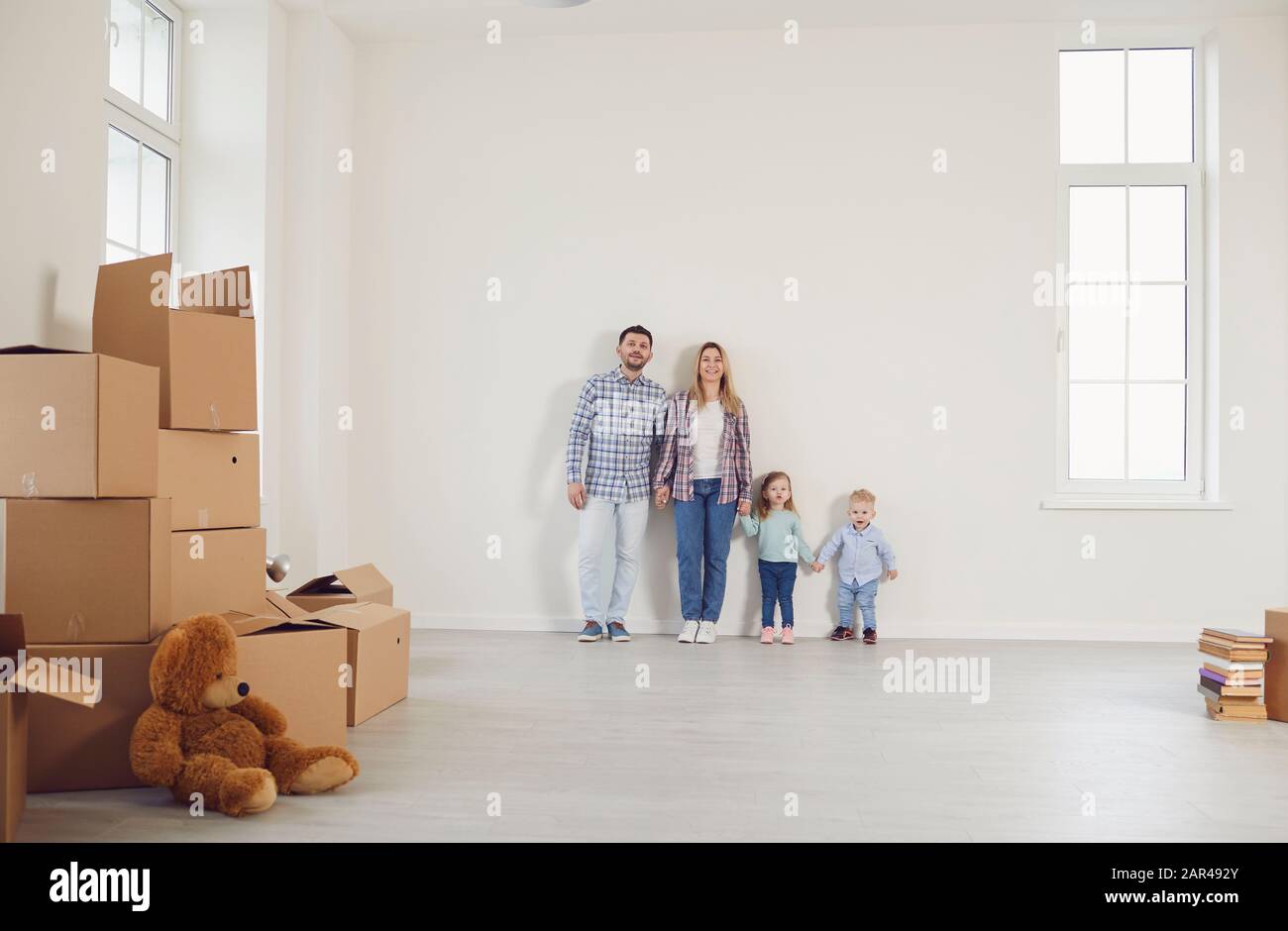 Happy family with children moving with boxes in a new apartment house. Stock Photo