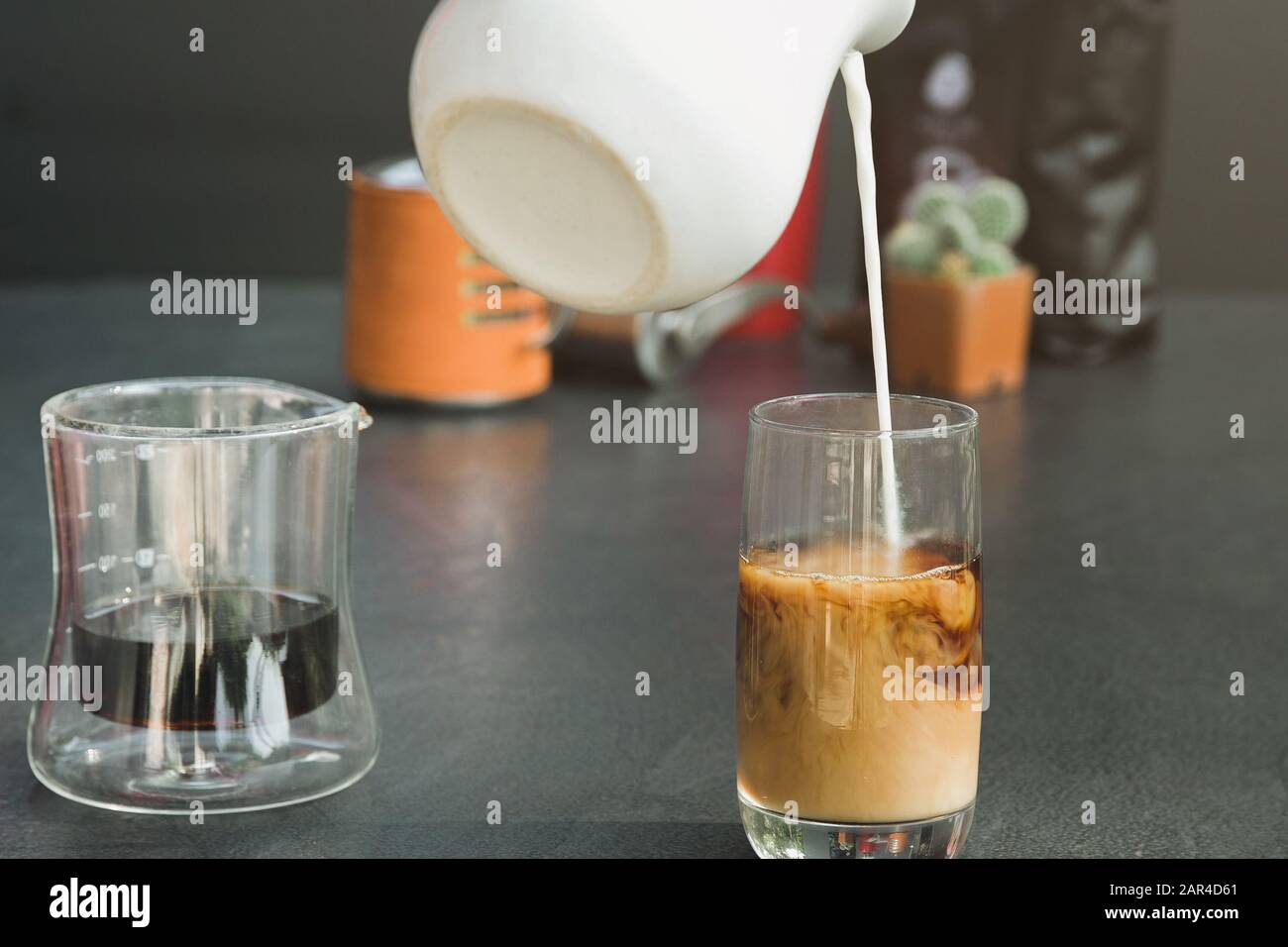 Pour fresh milk into a black coffee cup. Stock Photo