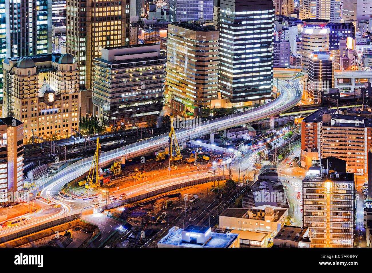 Urban cityscape of modern Japanese city Osaka at sunset with bright illumination of skyscraper towers and highways. Stock Photo