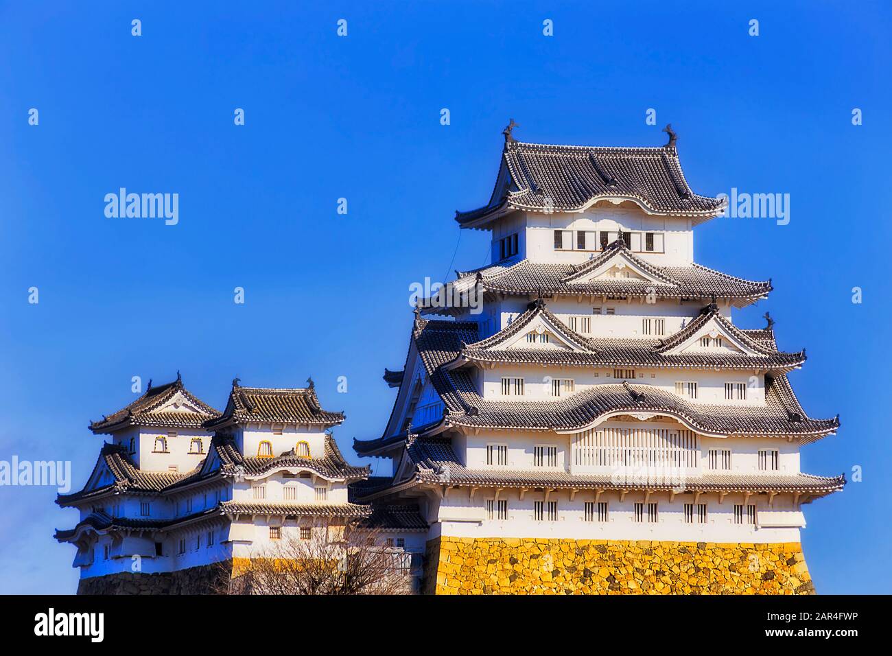 The main keep of the white castle in Japan near Osaka city agains blue sky in bright sun light - traditional japanese architecture. Stock Photo