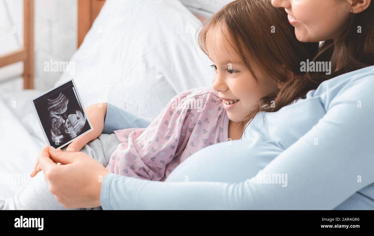 Cute little girl looking at ultrasound scan showed by mom Stock Photo