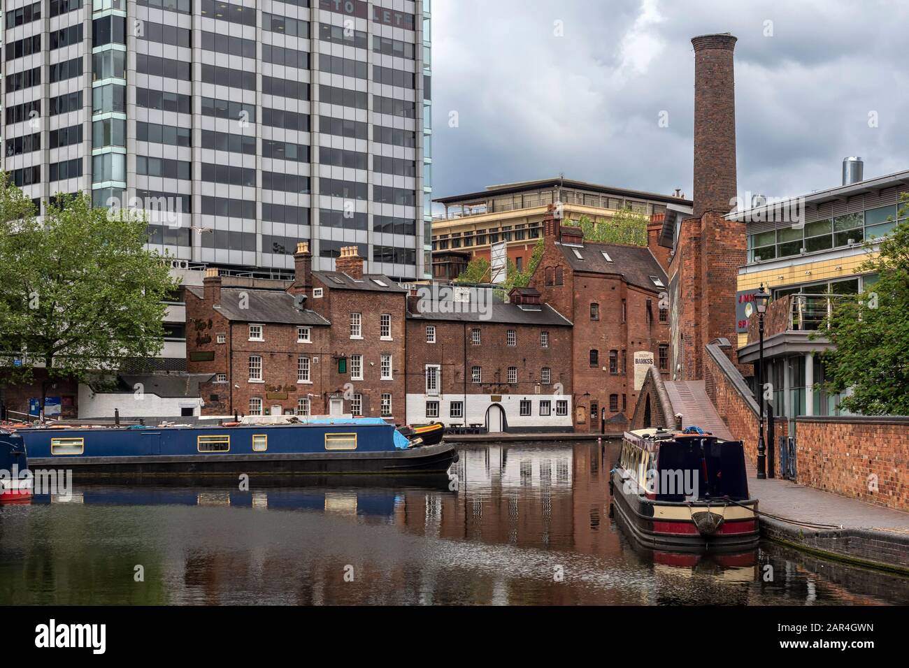 BIRMINGHAM, UK - MAY 28, 2019:  Narrowboats on the canal at Brindley Place surrounded by restored Victorian building and modern office buildings Stock Photo