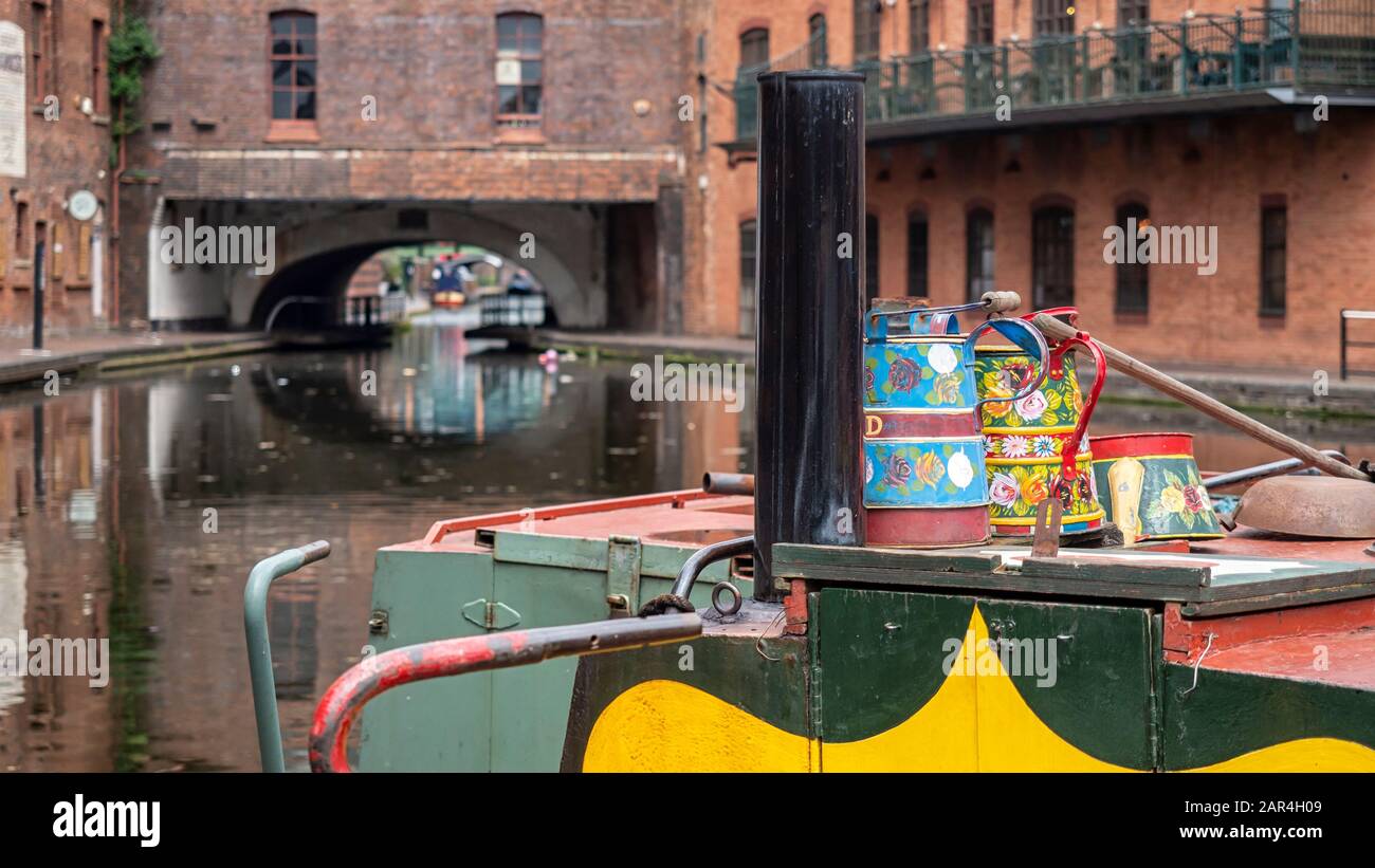 BIRMINGHAM, UK - MAY 28, 2019:  Traditional painted utensils on narrowboat moored on canal at Brindley Place with view of Victorian buildings Stock Photo
