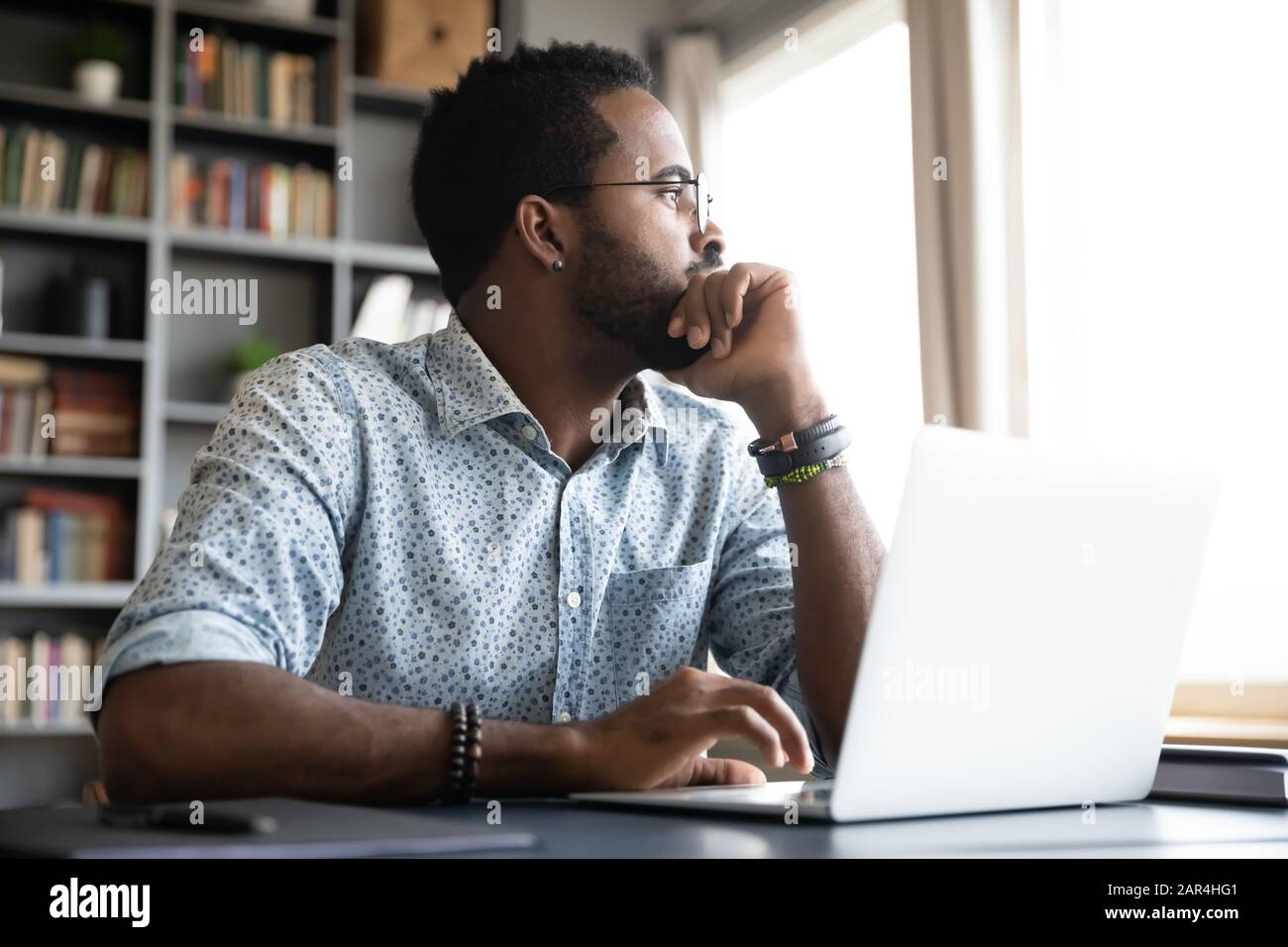 Thoughtful serious african man sit with laptop thinking of project Stock Photo