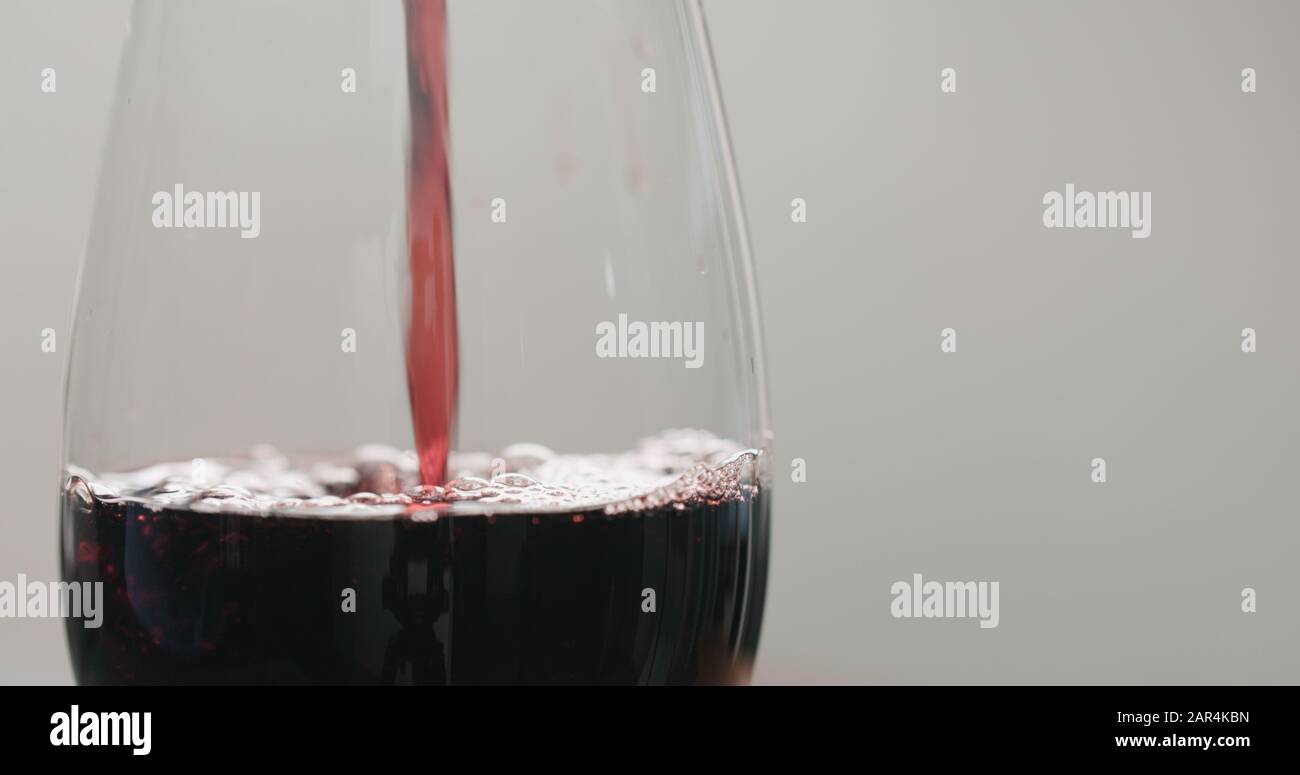 pour red wine into wine glass from bottle closeup , wide photo Stock