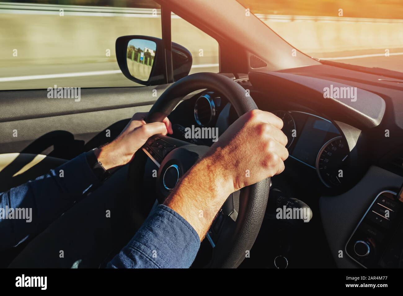 Close up shot of a man's hands holding a car's steering wheel Stock Photo